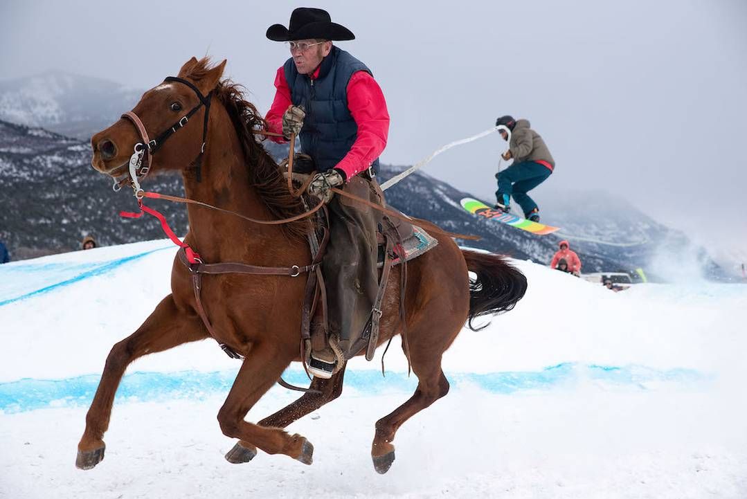 Image of horse and rider pulling a snowboarder